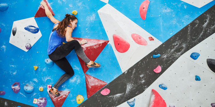 Junge Frau klettert auf einer bunten Kletterwand