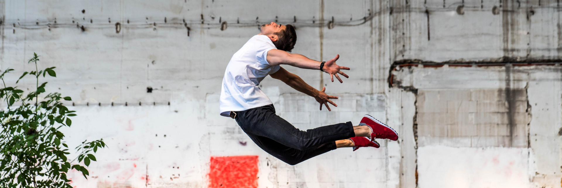 Ein junger Tänzer springt mit nach hinten gestreckten Beinen und Armen in die Luft